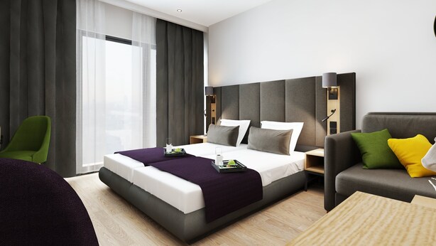A modern hotel room with a large bed, a sofa, a chair, and a desk. -  DIWOTEL by Trip Inn Frankfurt Airport Dreieich (Dreieich)
