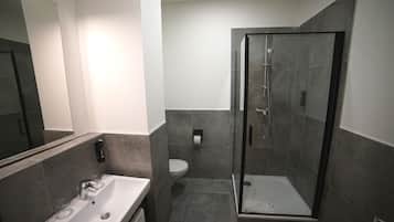 A modern bathroom with a glass-enclosed shower, a sink with a mirror, and a toilet.