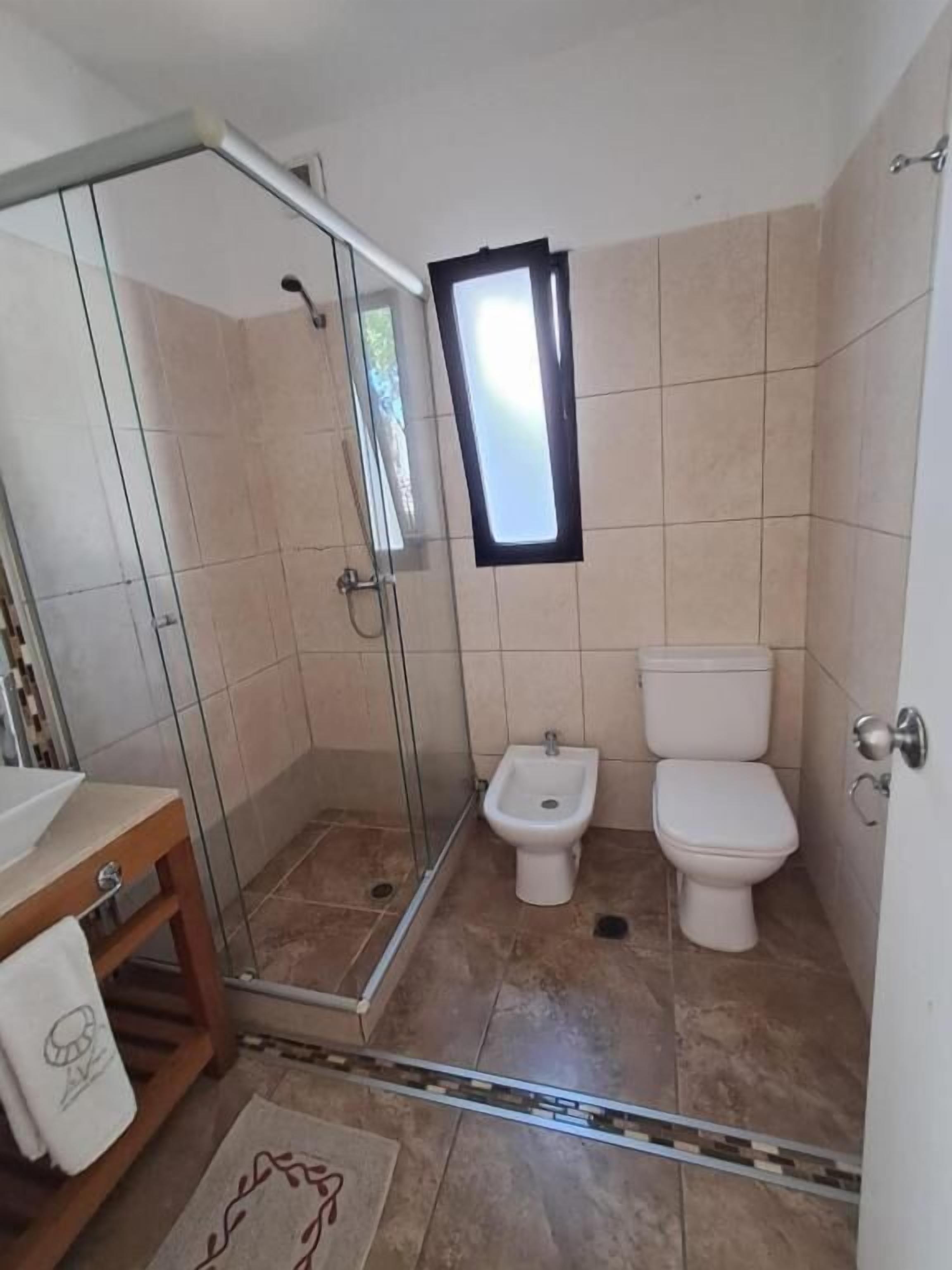 Une salle de bain avec une douche à parois de verre, un bidet et des toilettes.