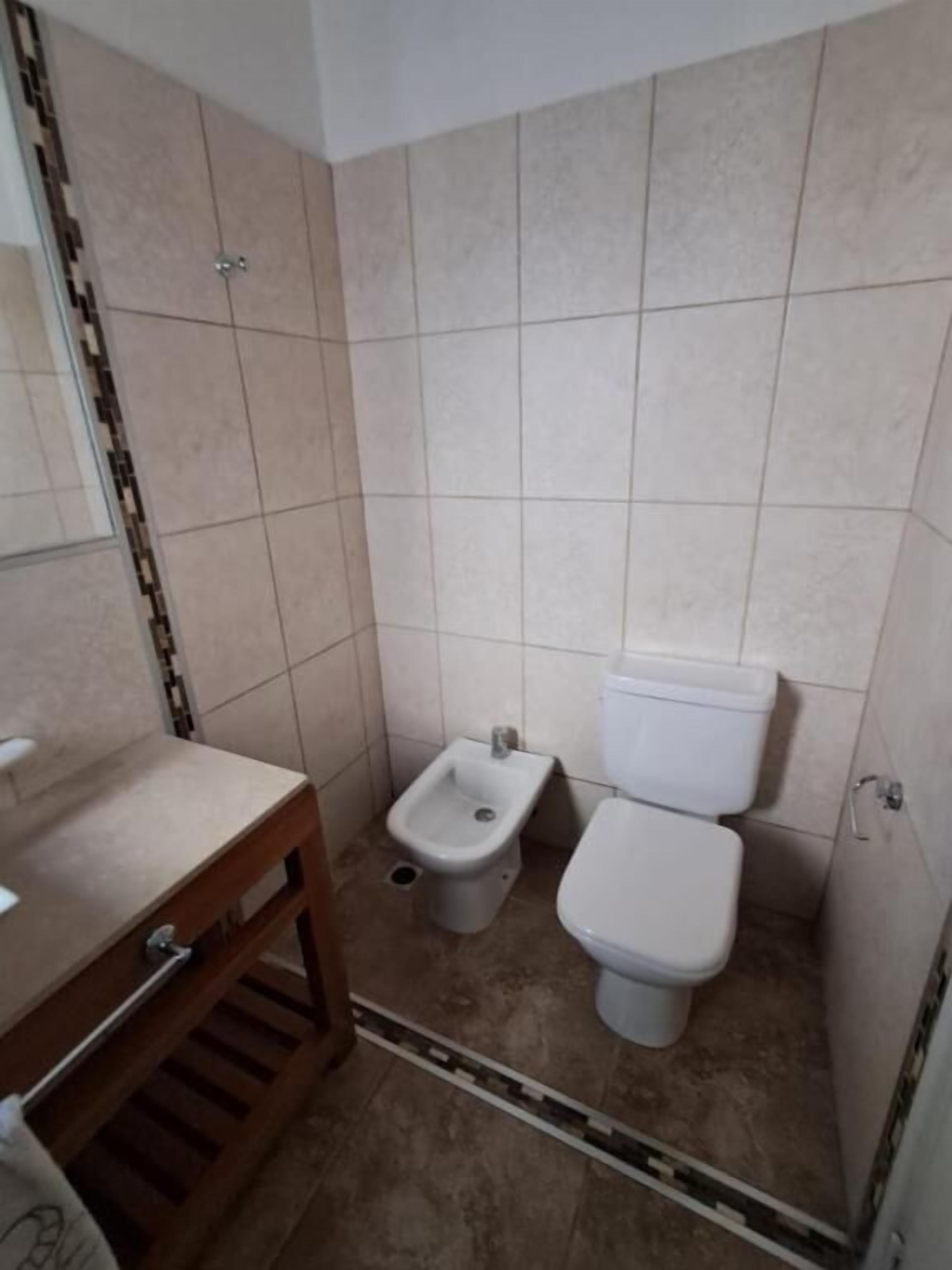 A small bathroom with a toilet, bidet, and a wooden vanity.