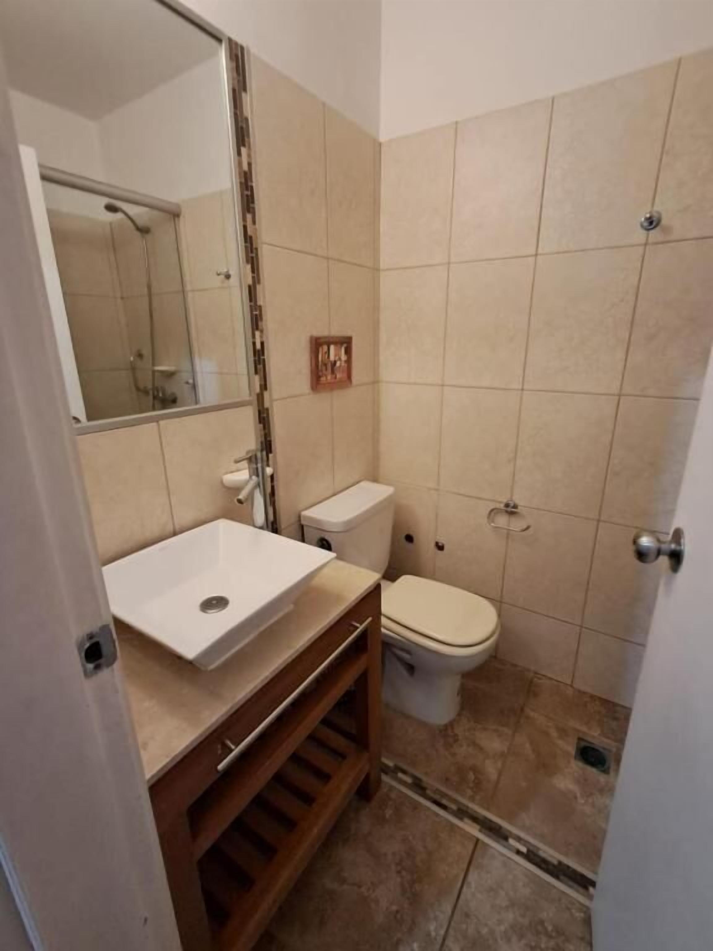 A bathroom with a white sink, toilet, and shower.