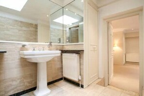 Casa de banho moderna com lavatório assentado, espelho na parede e radiador visível.