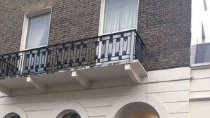 A townhouse with a black front door, a balcony with black railings, and a number '55' above the door.