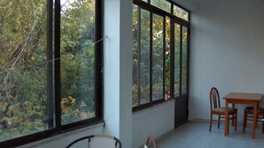 A room with a balcony, a table, two chairs, and a glass table. - Red Sun (Chios)