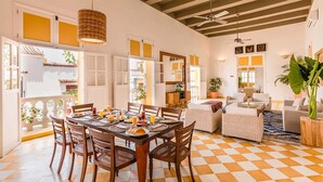 Un coin repas avec un sol à carreaux, une table ronde entourée de chaises et un luminaire suspendu.