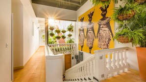 Un escalier avec une balustrade blanche menant à un palier orné d’une fresque murale jaune.