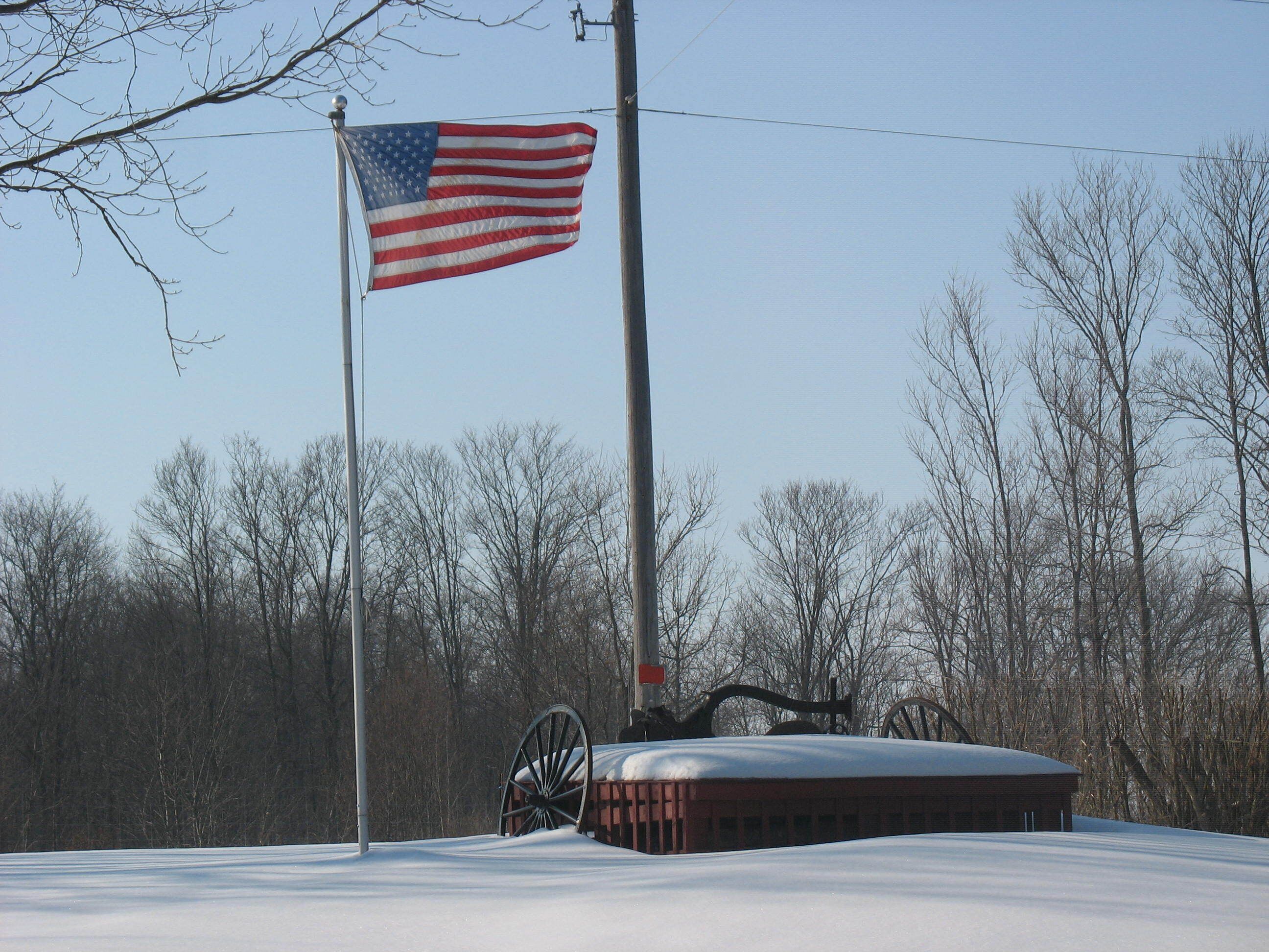 Een gebouw bedekt met sneeuw, met een grote Amerikaanse vlag op een vlaggenmast.
