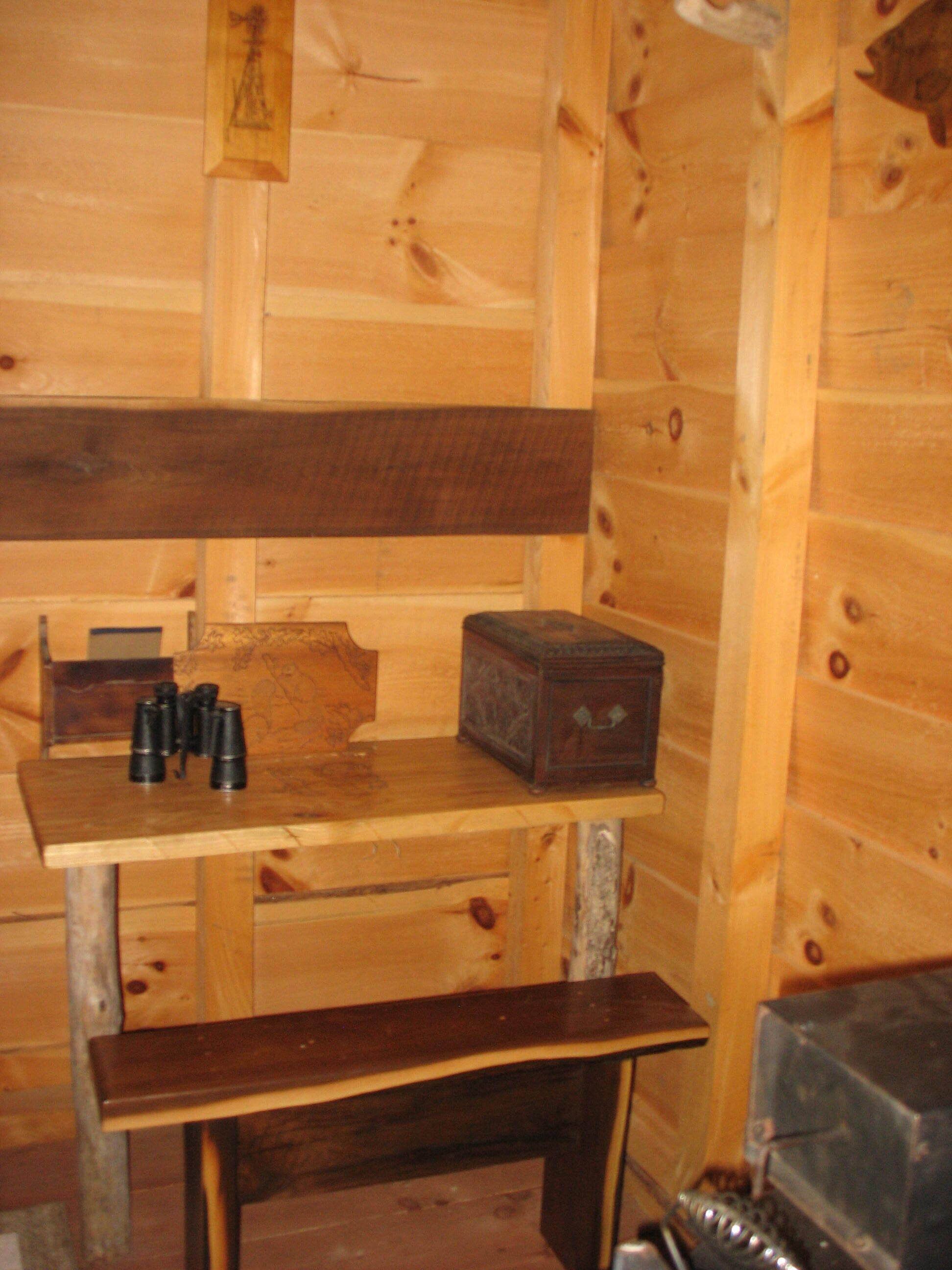 A wooden cabin interior with a bench, a small table, and a box.