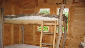 A bunk bed in a wooden cabin room with two windows and a small table. - Unplug at cabin for 2 (Polk)