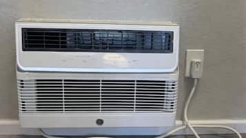 A white portable air conditioner unit with a control panel, connected to a power outlet.
