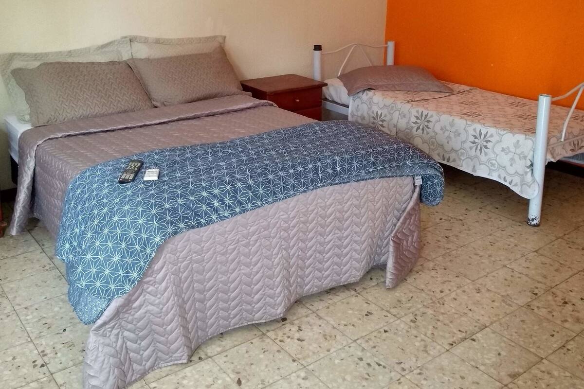 A bedroom with two beds, a nightstand, and a dresser.