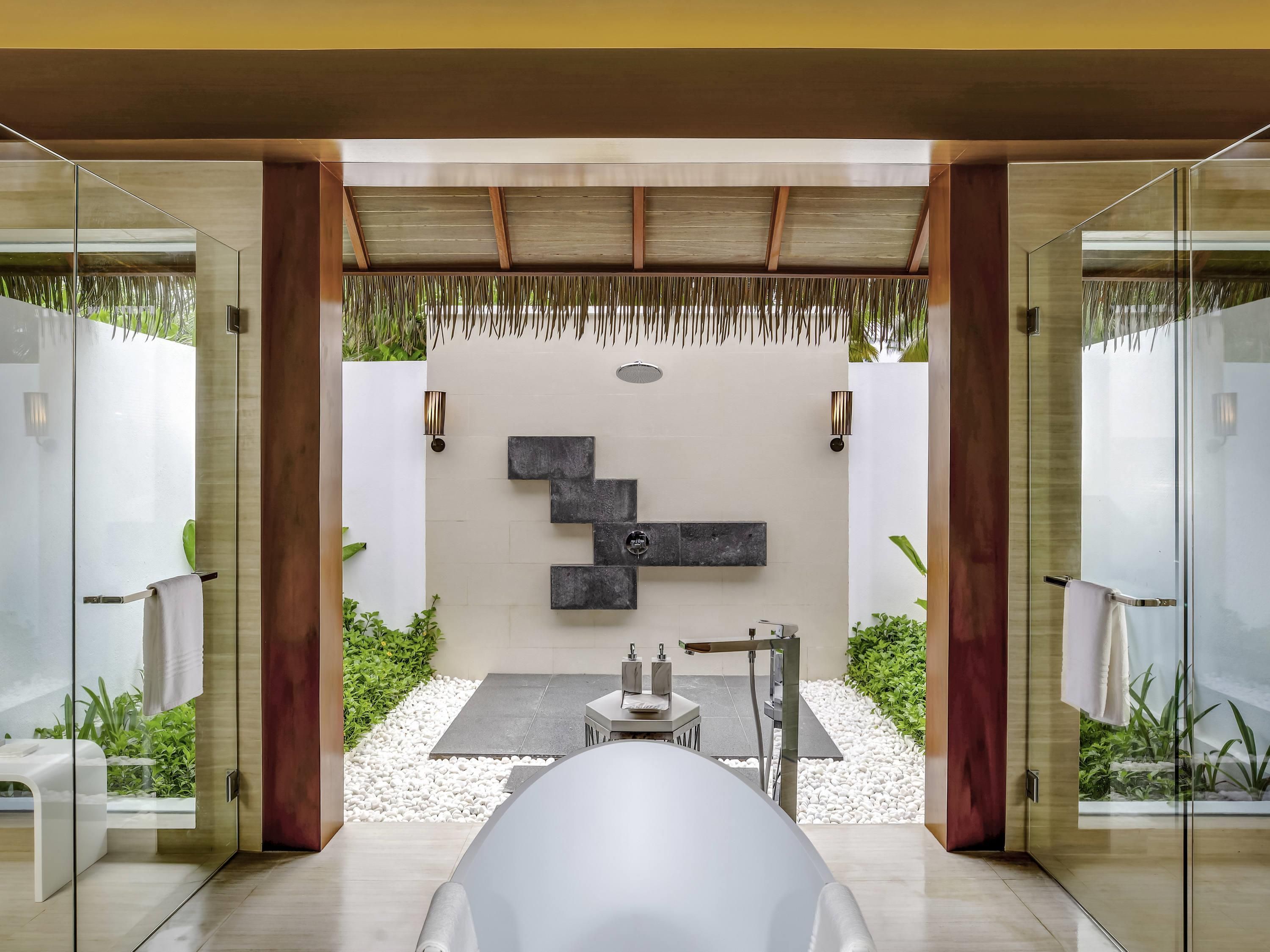 Une salle de bain moderne avec une paroi de verre, une baignoire blanche et un design minimaliste.