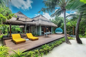 A tropical resort with a wooden deck, yellow lounge chairs, a thatched-roof structure, and a pool area. - Pullman Maldives Resort (Maamutaa Island)