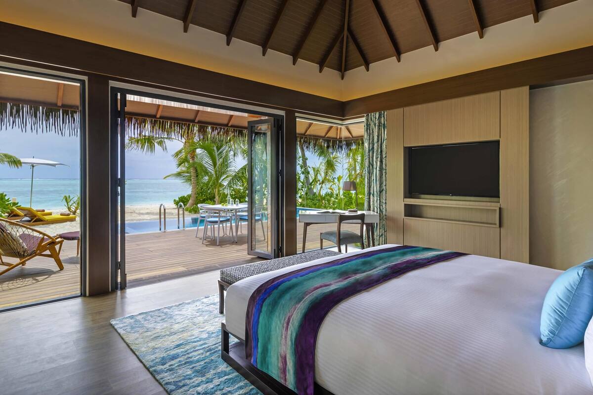 Un dormitorio con una cama grande, televisión y vista a la playa.