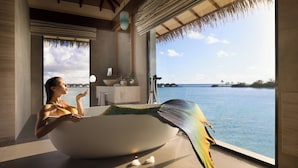A woman relaxing in a bathtub with a view of the sea. - Pullman Maldives Resort (Maamutaa Island)