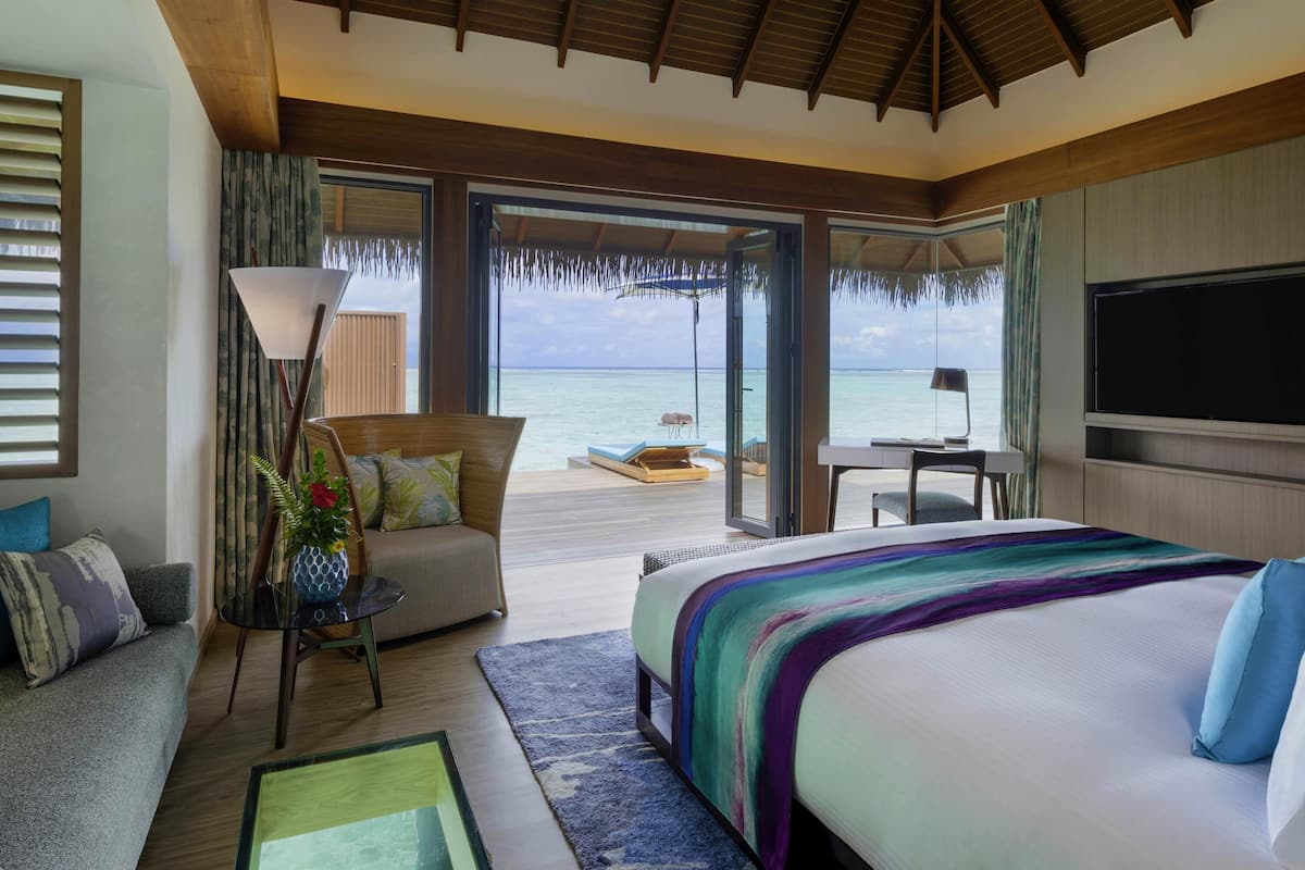 Una habitación de hotel con una cama grande, un escritorio, una silla, un sofá y vistas al océano.