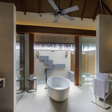 A modern bathroom with a freestanding bathtub, glass shower enclosure, and a ceiling fan.