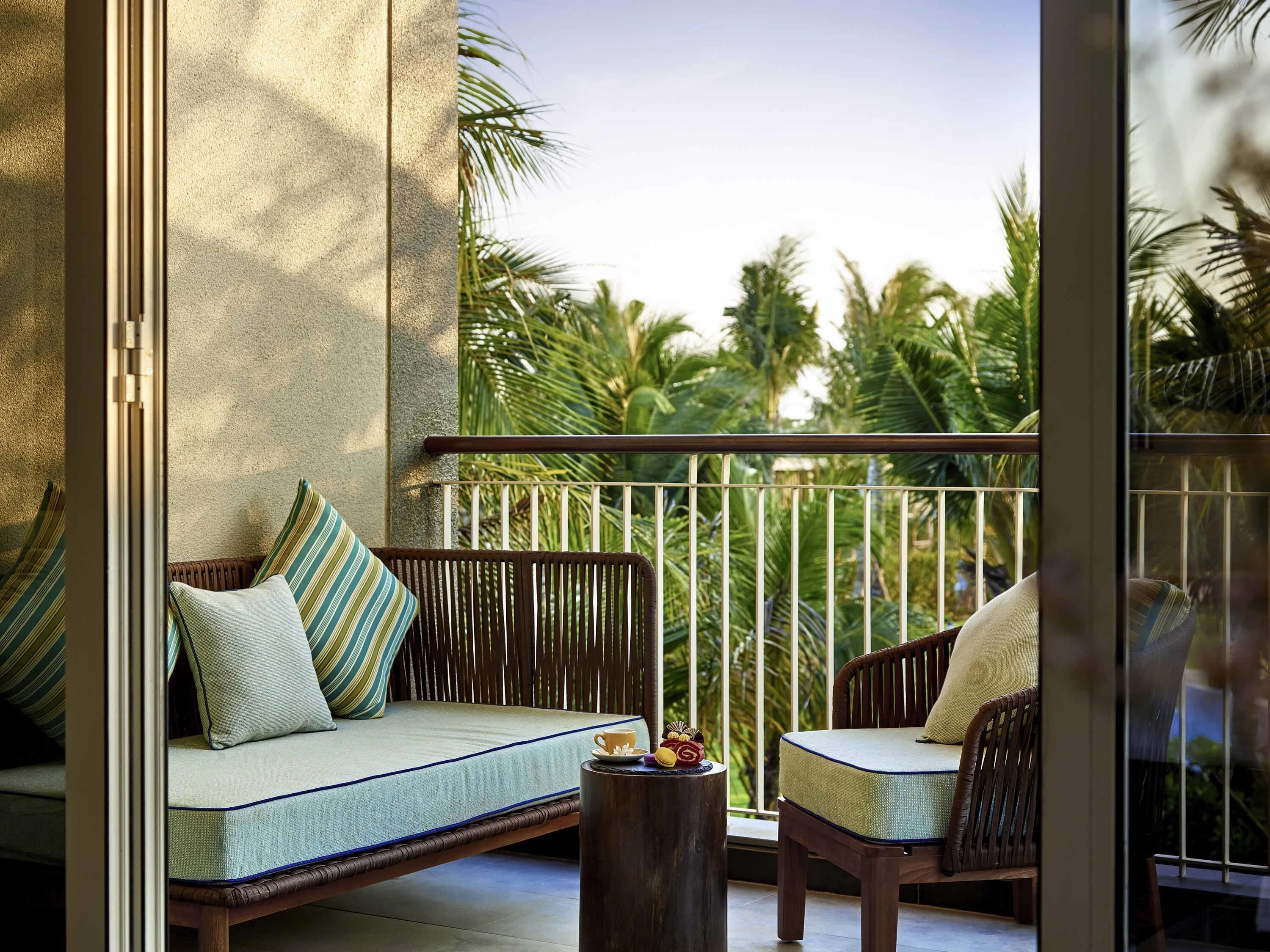 Un balcon avec un canapé, des chaises et une petite table sur laquelle se trouvent une tasse et un objet décoratif.