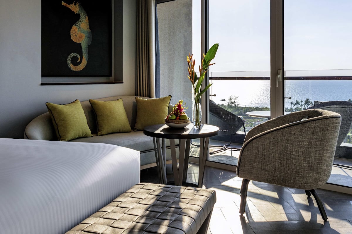 Ein Hotelzimmer mit einem Bett, einem Sofa, einem kleinen Tisch mit einer Vase und einem Sessel.