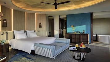 Een moderne hotelkamer met een groot bed, een zithoek, een ronde tafel met een koffiekop, en een badkamer zichtbaar door een geopende deur.