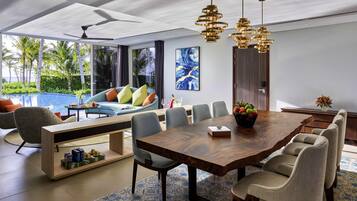 A modern dining area with a wooden table, grey chairs, and a decorative bowl of fruit.