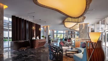 Eine moderne Lobby mit einer Rezeption, Sitzbereichen und großen Fenstern.