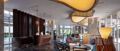 A modern lobby with a reception desk, seating areas, and large windows.