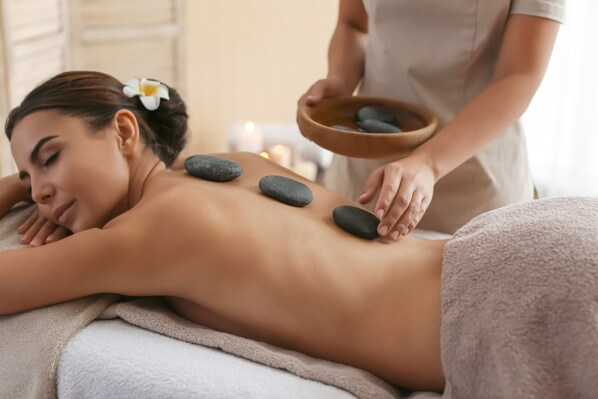A person receiving a stone massage with a bowl of stones nearby. - Pullman Phu Quoc Beach Resort (Phu Quoc)