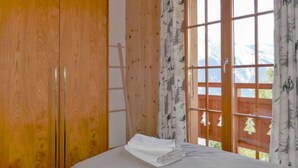 Una stanza con pareti in legno, un letto con biancheria bianca e una finestra vista montagne.