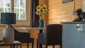 A cozy room with a wooden interior, a table with two chairs, a vase with sunflowers, and a lamp. - House Halfway to Veere (Veere)