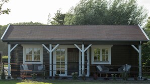 A wooden cabin with a porch, two chairs, and a small table. - House Halfway to Veere (Veere)