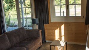 A living room with a brown sofa, a small table with a remote control, and a lamp. - House Halfway to Veere (Veere)