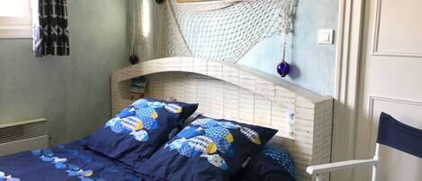 Um quarto com uma cama, uma rede e uma cadeira.