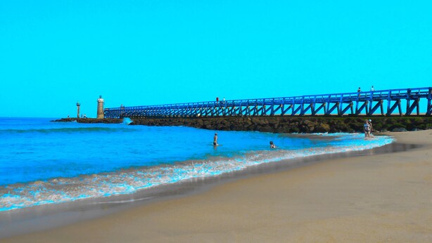A beach with a pier extending into the water, featuring a lighthouse and rocky outcrops. - Nice Capbretonnaise three rooms between port, trade, and beach (Capbreton)