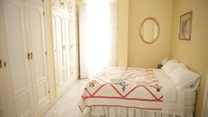 A bedroom with a bed, a mirror, and a wardrobe. - Casa Patio del Panadero (Cádiz)