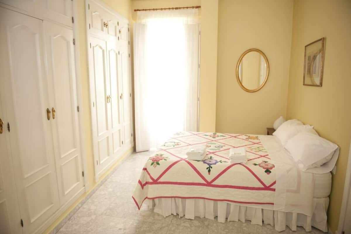 A bedroom with a bed, a mirror, and a wardrobe.