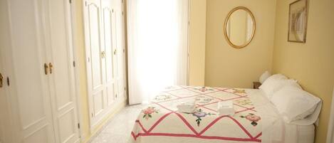 Une chambre à coucher avec un lit, un miroir et une armoire.