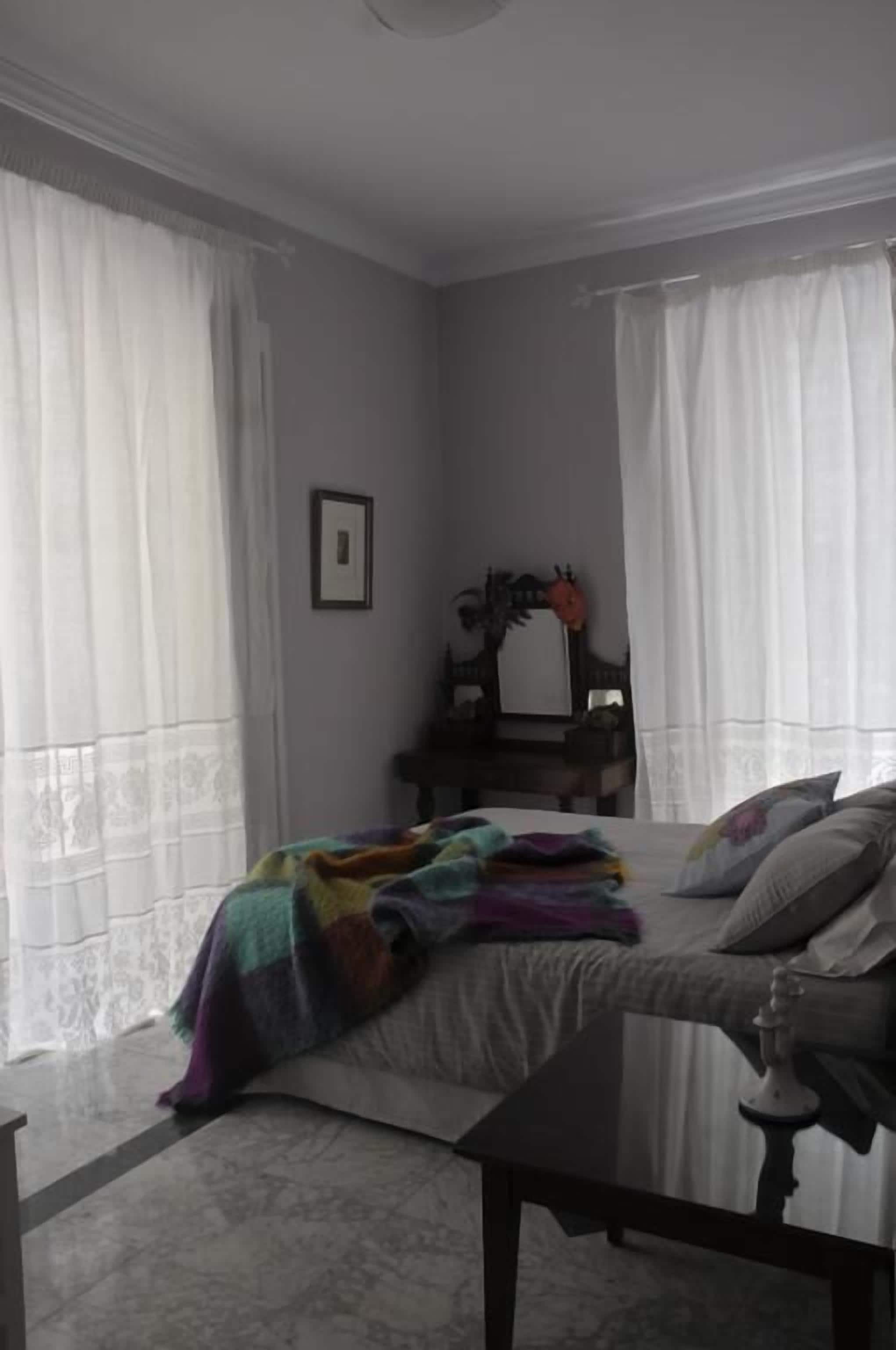 A bedroom with a bed, a bedside table, a dresser, and a mirror.