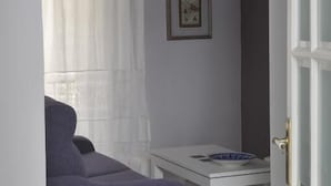 A modern living room with a purple sofa, a white coffee table, and a pendant light. - Casa Patio del Panadero (Cádiz)