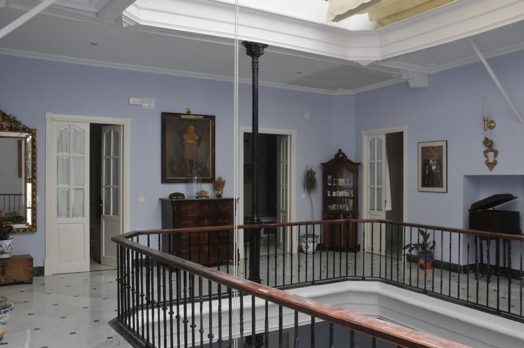 Una habitación amplia con techo alto, una columna central y una escalera que lleva a un nivel superior.