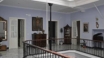 Una habitación amplia con techo alto, una columna central y una escalera que lleva a un nivel superior.