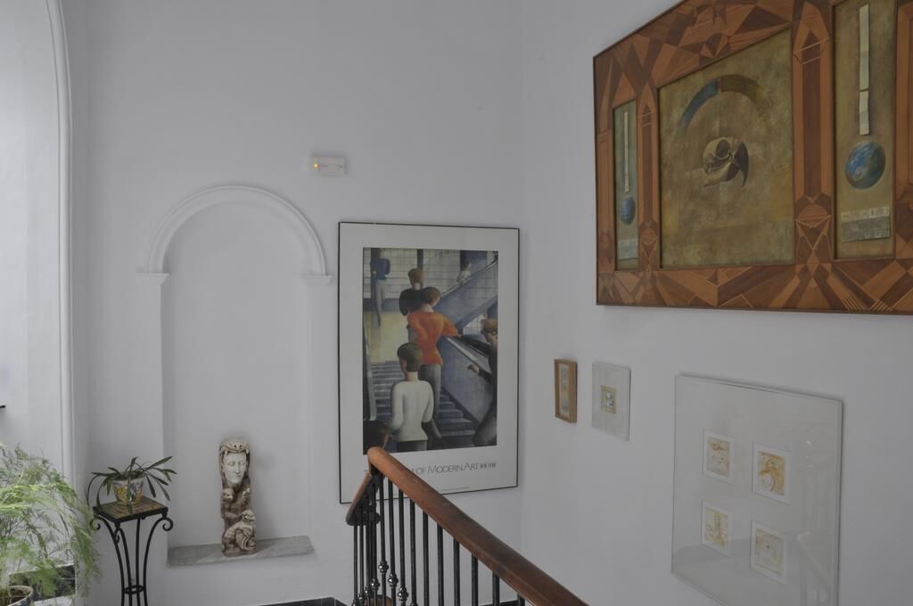 A staircase with a handrail, a wall-mounted artwork depicting people, and a decorative panel with geometric patterns.