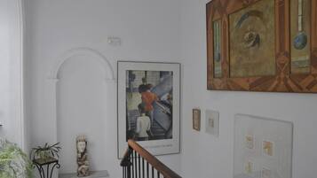 A staircase with a handrail, a wall-mounted artwork depicting people, and a decorative panel with geometric patterns.