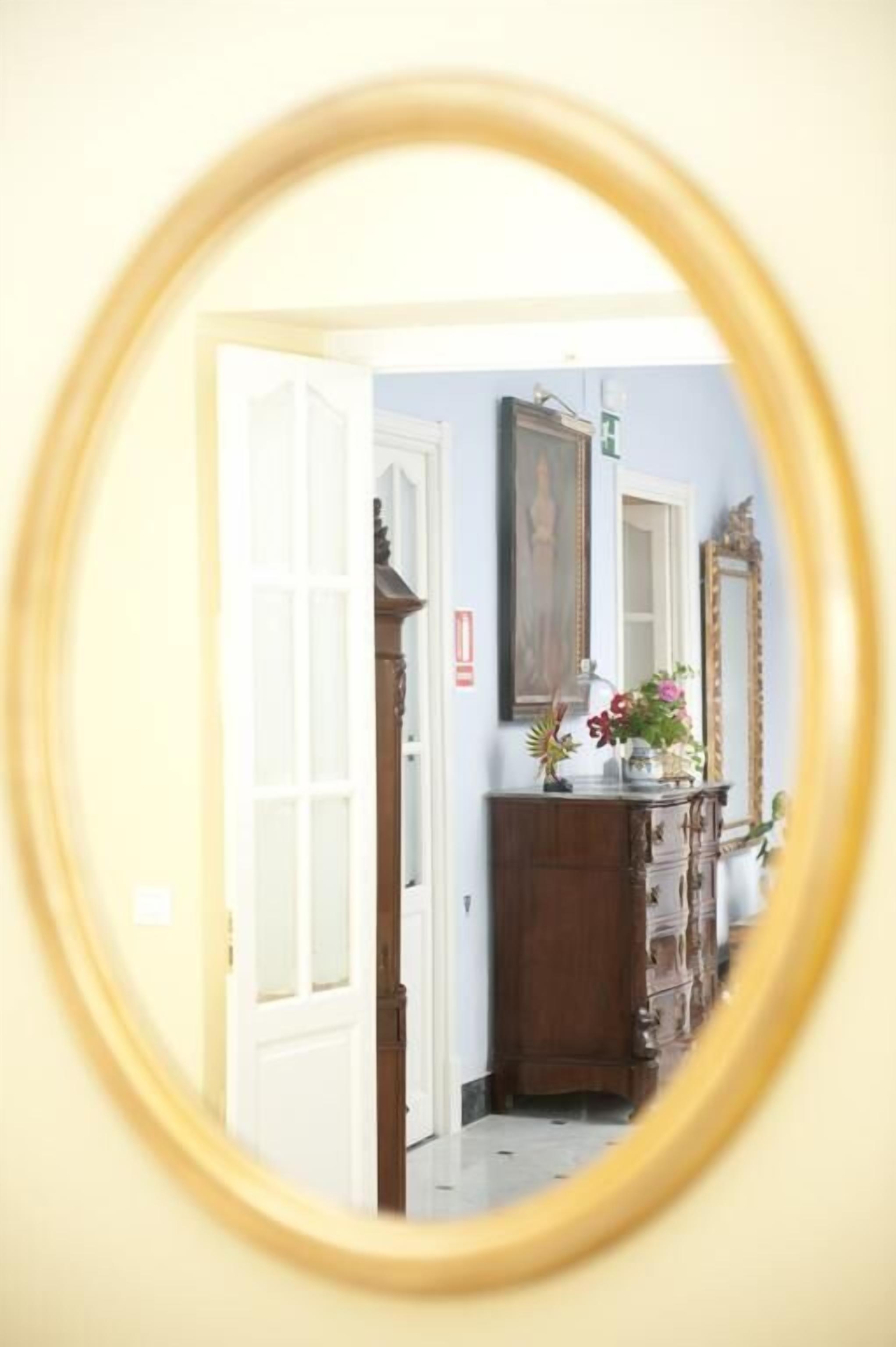 Un pasillo con un aparador de madera, un espejo y una puerta que da a otra habitación.