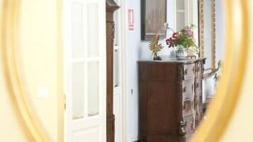 Un pasillo con un aparador de madera, un espejo y una puerta que da a otra habitación.
