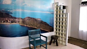 Ein Zimmer mit einer großen Wandmalerei von einer Küstenlandschaft, einem blauen Stuhl und einem kleinen Hocker.