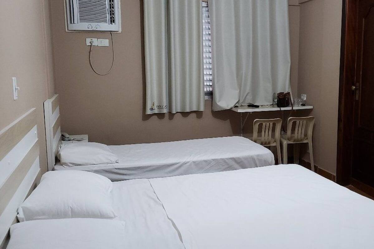 A hotel room with two beds, a desk, a chair, and a mirror.