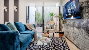 A modern living room with a blue sofa, a coffee table with magazines, and a TV mounted on the wall. - Illumé Urban Living - Apartments in the heart of Roma Norte (Mexico City)