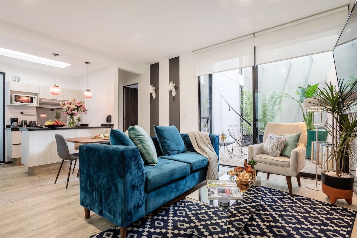 Ein modernes Wohnzimmer mit einem blauen Sofa, einem Couchtisch und einem Essbereich.
