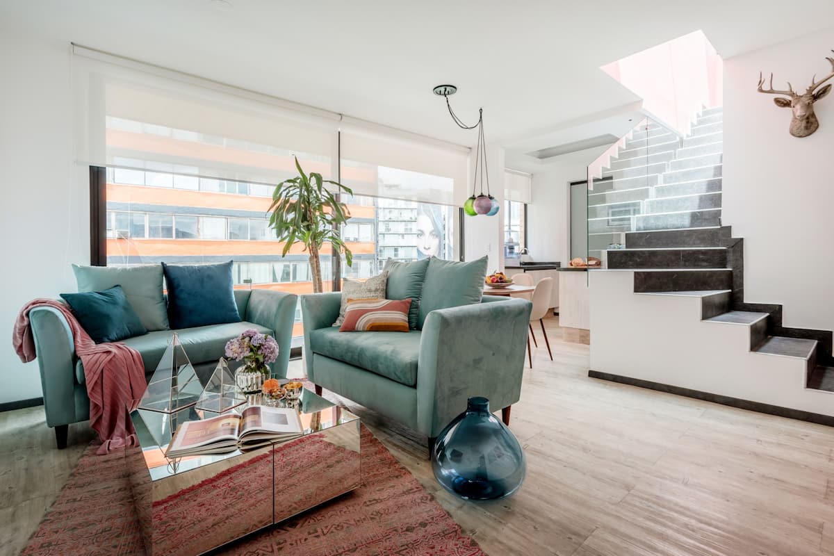 Ein modernes Wohnzimmer mit einem grünen Sofa, einem Glastisch und einem großen Fenster.